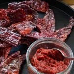 Red chilli paste in bowl on tray with dried chillies