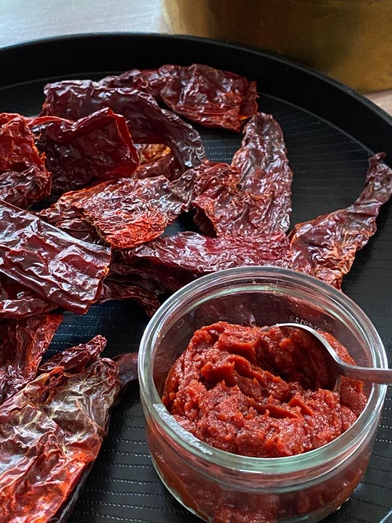 Red chilli paste in bowl on tray with dried chillies