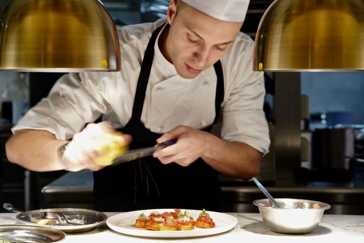 chef grating cheese over pasta