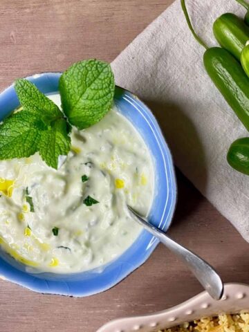 cacik in blue bowl alongside cucumbers