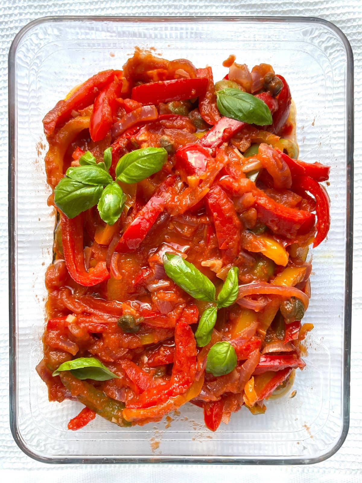 Peperonata with fresh basil in a large glass dish.