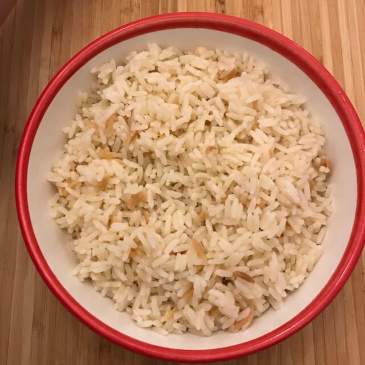Turkish rice in a white bowl with red rim on a table
