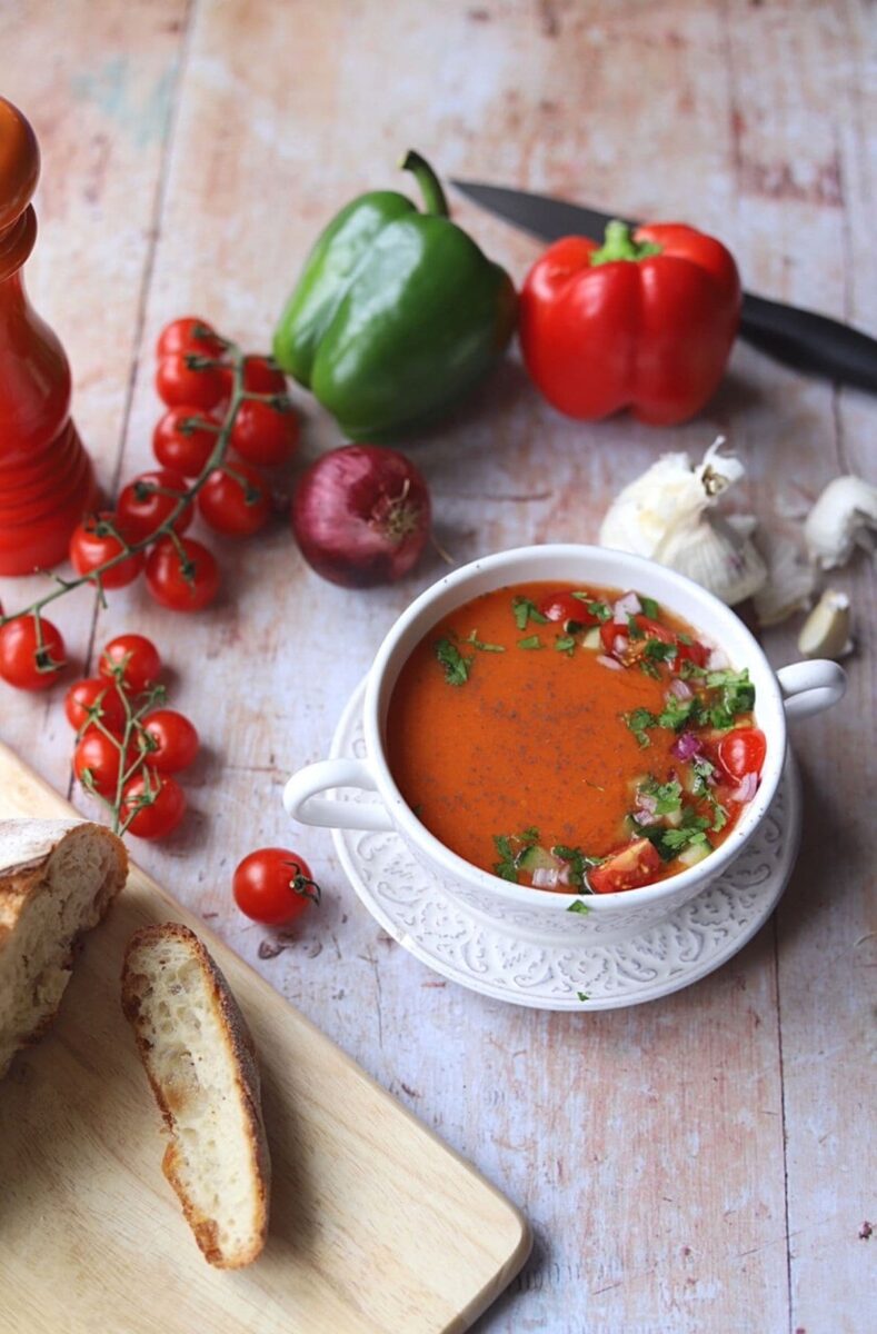 Gazpacho surrounded by fruit, vegetables and bread