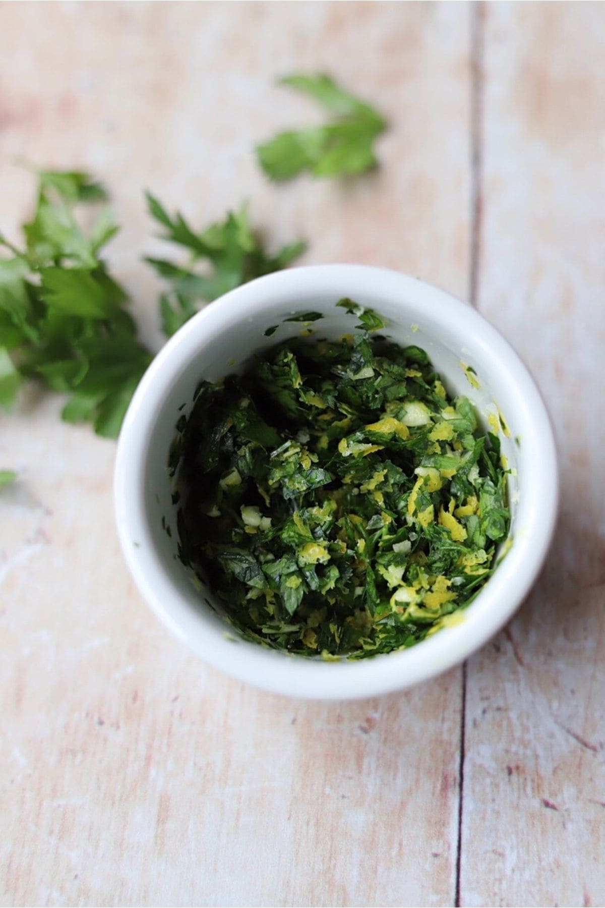 Gremolata in small white bowl on wooden table