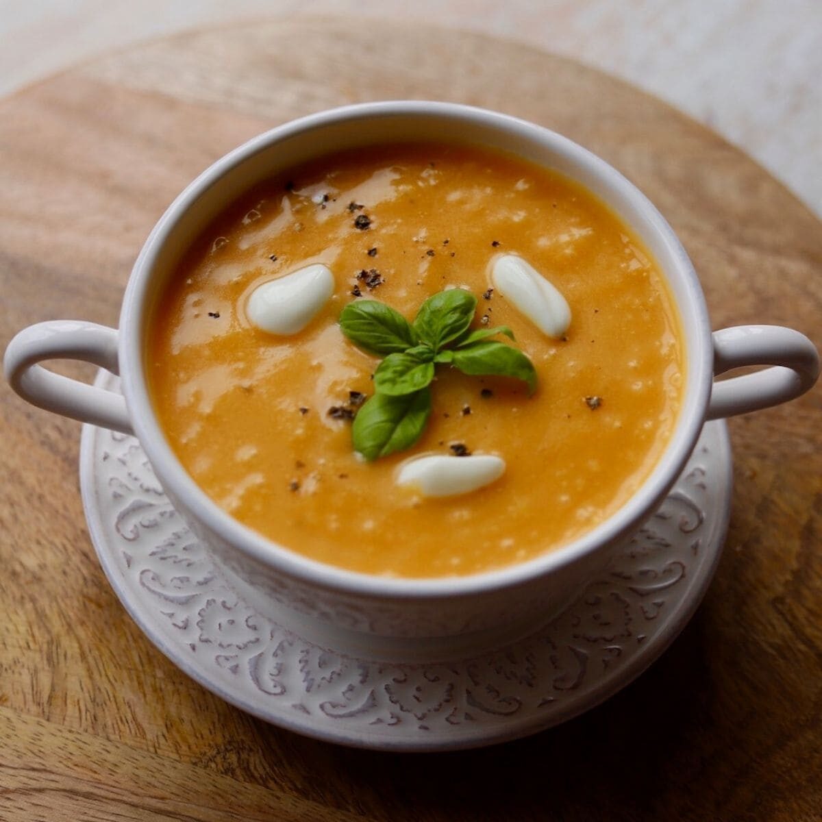 Soup in white bowl on wooden board