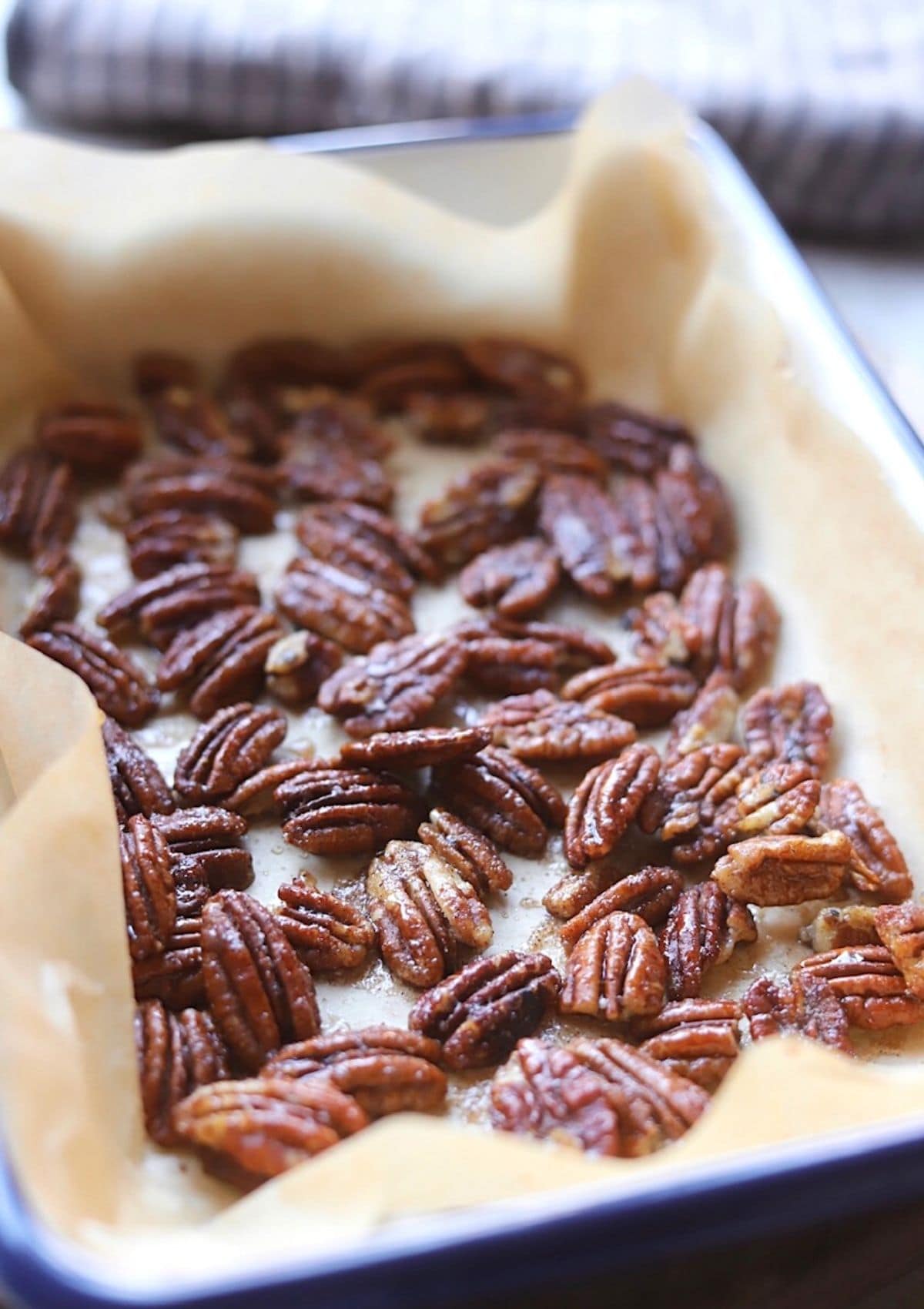 Honey roasted pecans in roasting dish on parchment paper.