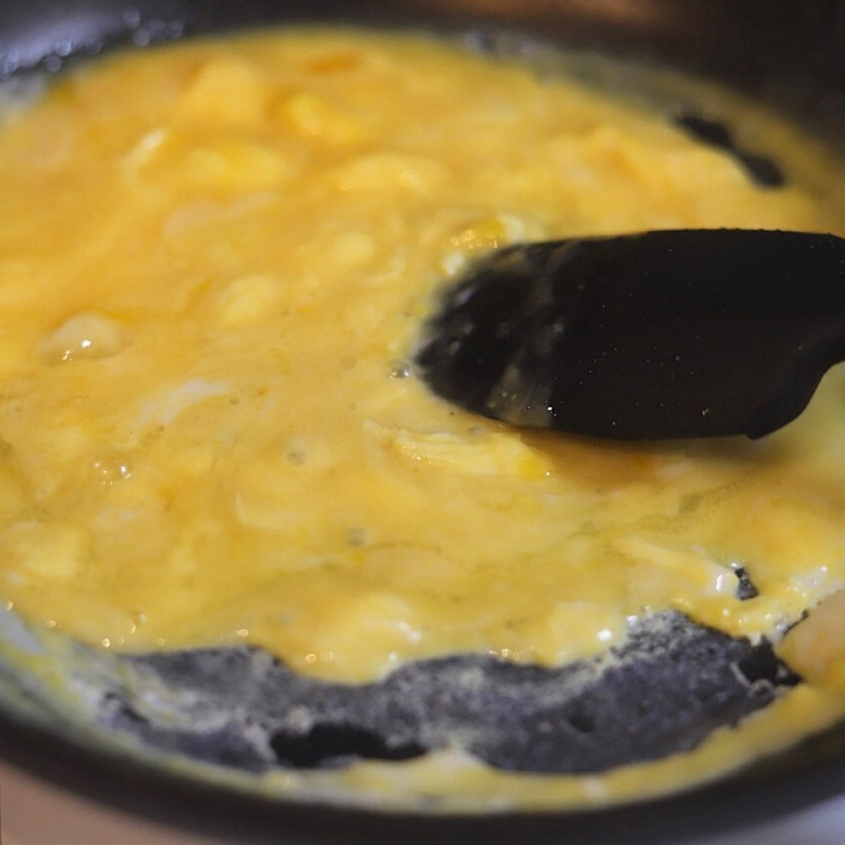 Scrambling eggs in a non stick skillet pan with a silicon spoon.