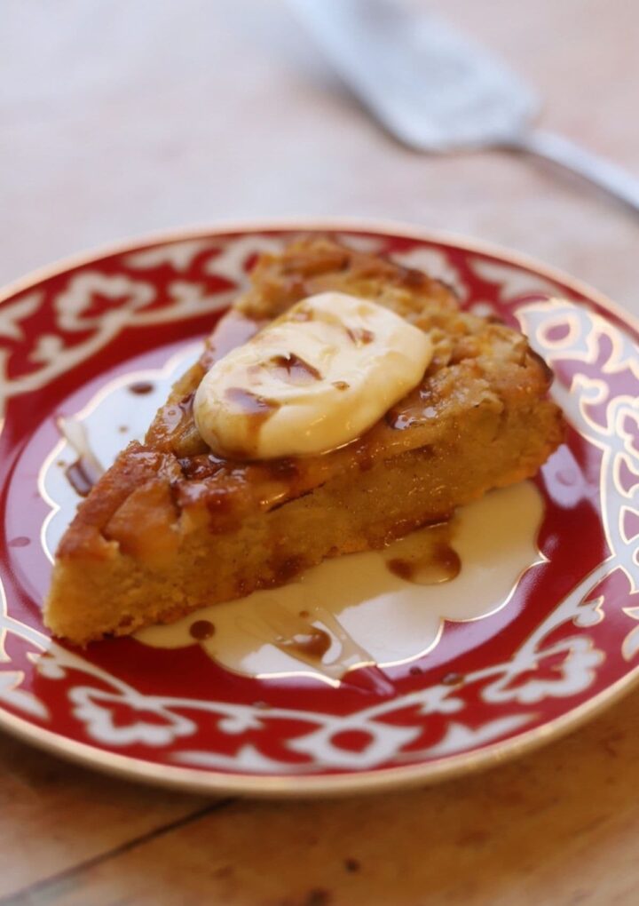 Slice of apple polenta cake with creme fraiche, on a plate