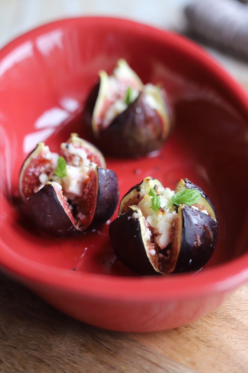 Roasted stuffed figs in red baking dish.