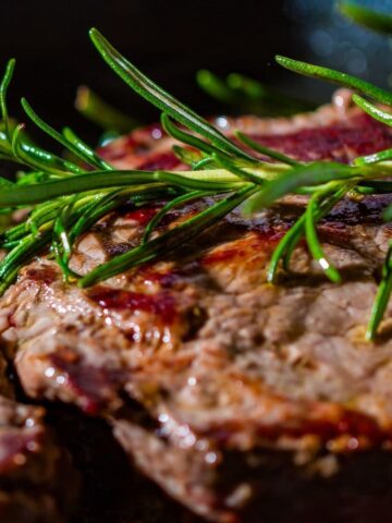 Image of closeup of grilled meat with herbs.