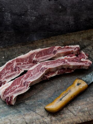 Image of cuts of meat next to a knife on chopping board.