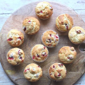 Image of orange cranberry muffins on wooden board.