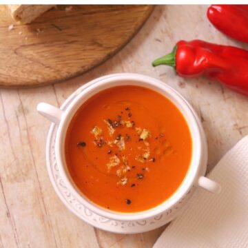 Image of roasted red pepper soup in white bowl.