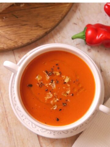 Image of roasted red pepper soup in white bowl.
