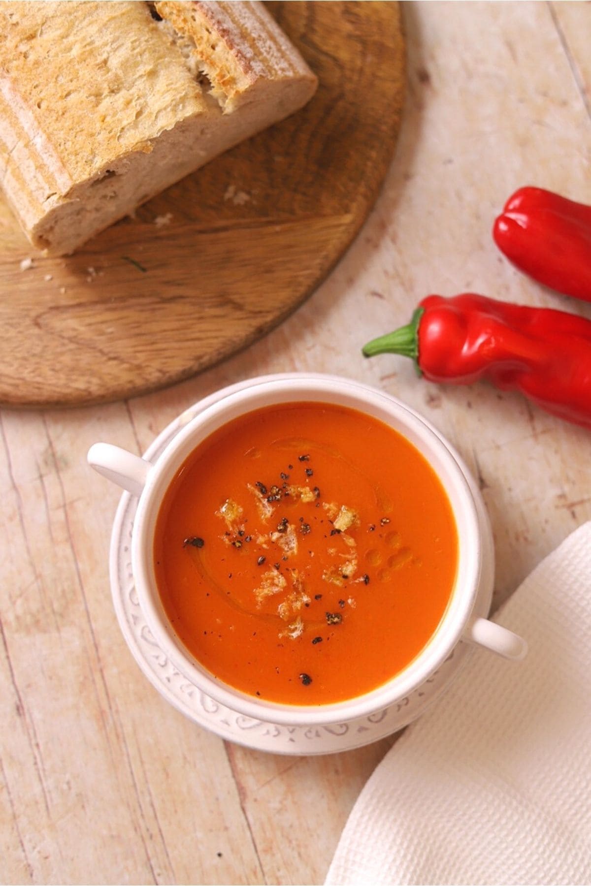 Overhead view of red pepper soup in white bowl