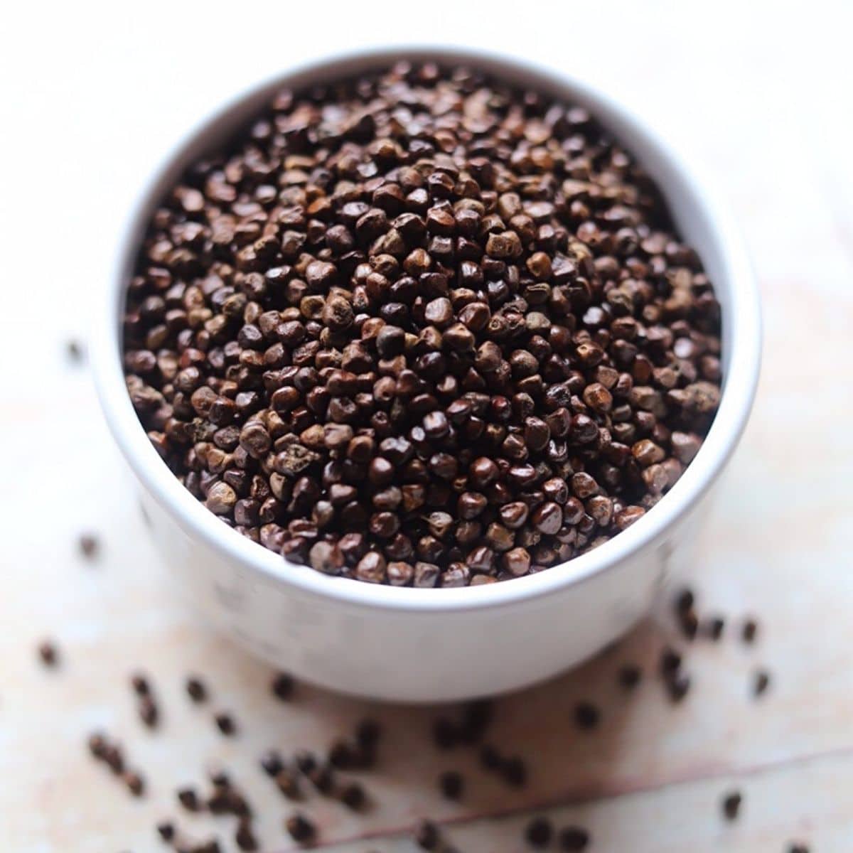 Dark brown Korarima seeds in white bowl