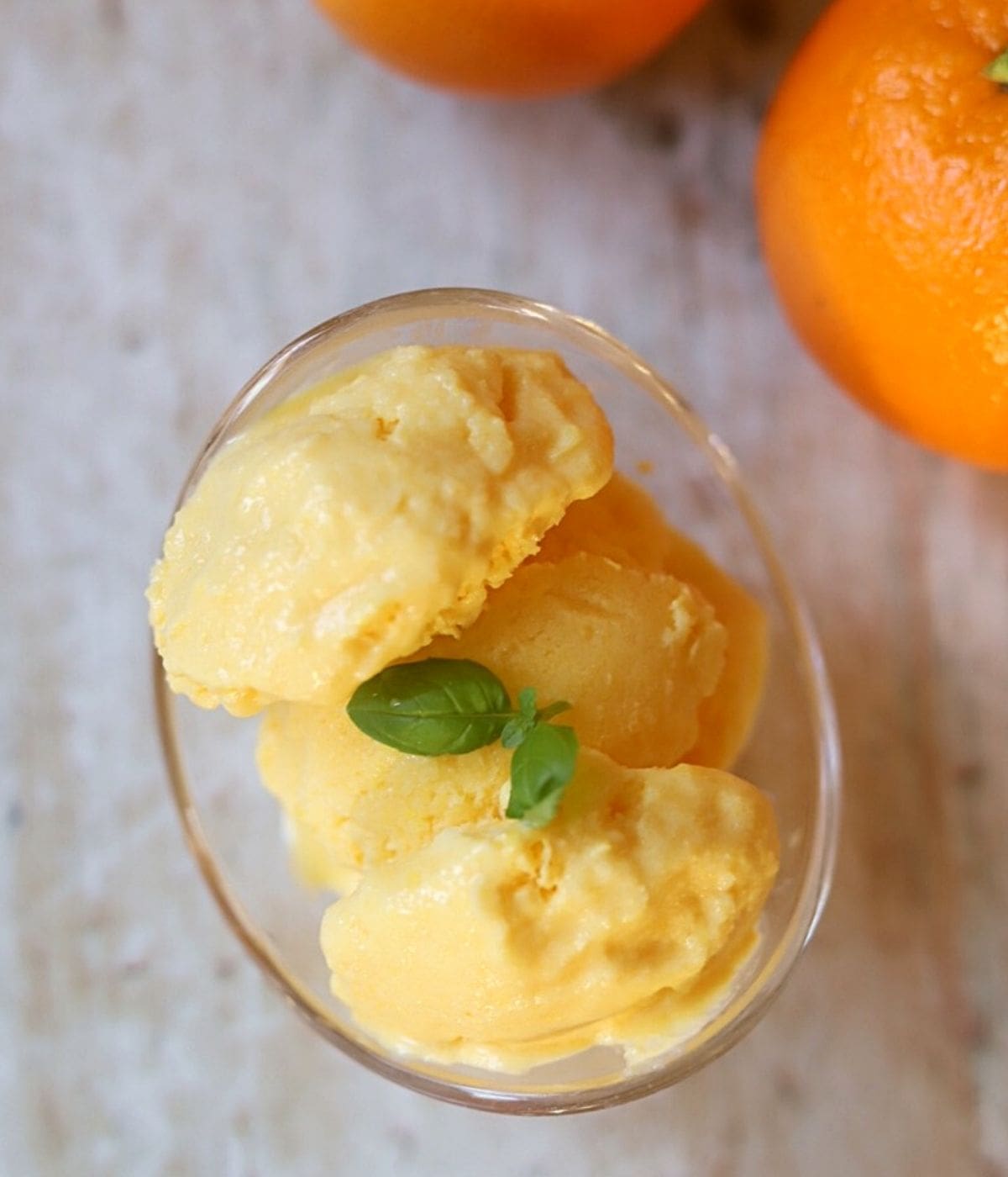 Orange frozen yogurt in glass bowl with basil