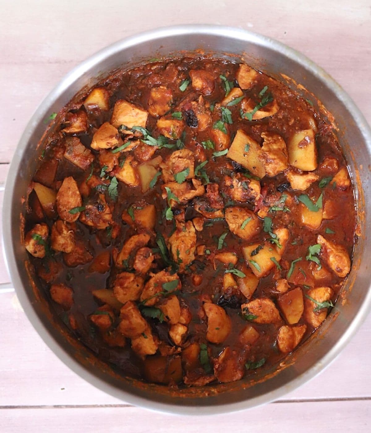 Chicken curry in a large saucepan with chopped cilantro.