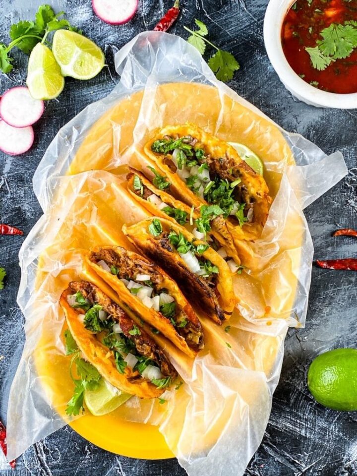 Image of birria tacos on a large yellow platter.