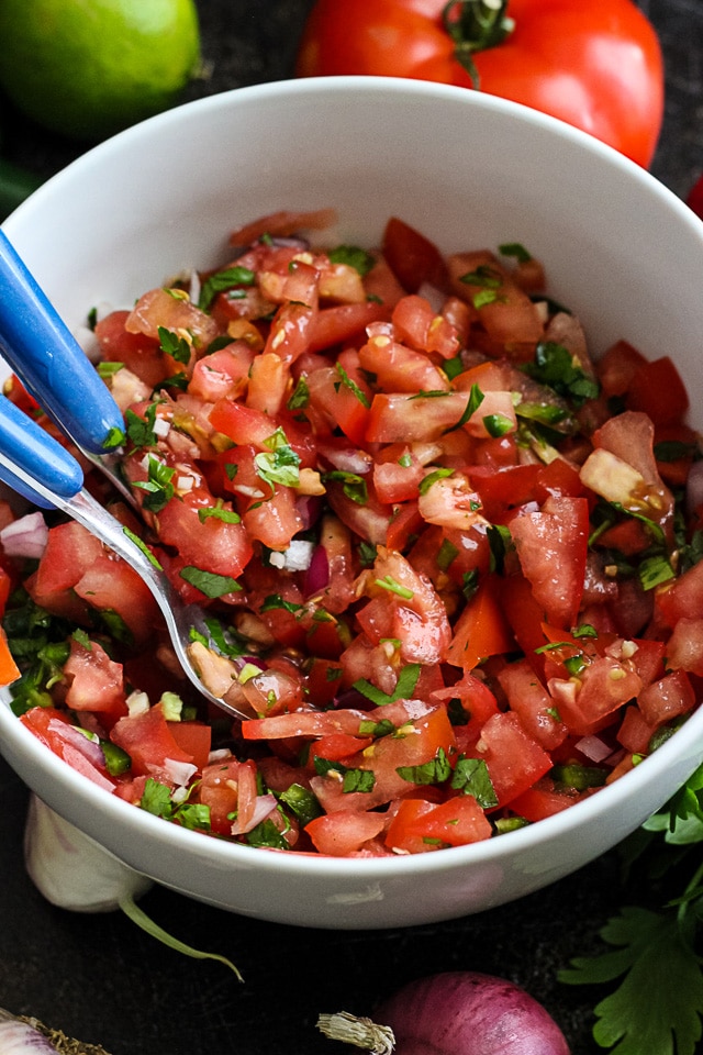 Image of fresh tomato salsa in white bowl with cutlery.