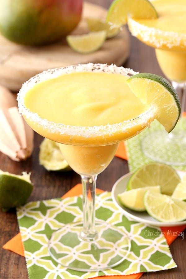 Image of two mango coconut frozen margaritas in a glass with slice of lime.