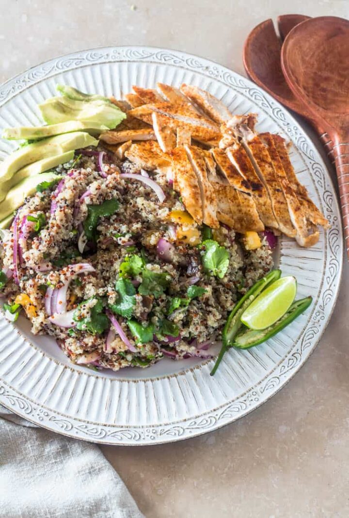 Image of Mexican quinoa with grilled chicken and avocado slices on a white plate.