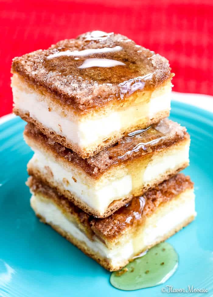 Image of a stack of three sopapilla cheesecake bars on a blue plate.