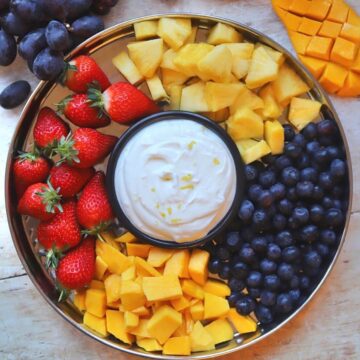 Image of fruit platter with small bowl of honey yogurt dip in the middle.