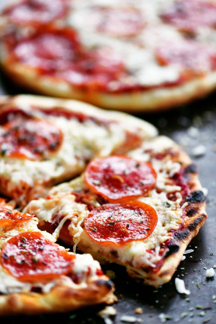 Side view of two grilled pizzas with pepperoni.