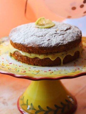 Image of banana cake with slice of lemon and sprinkles on a cake stand.