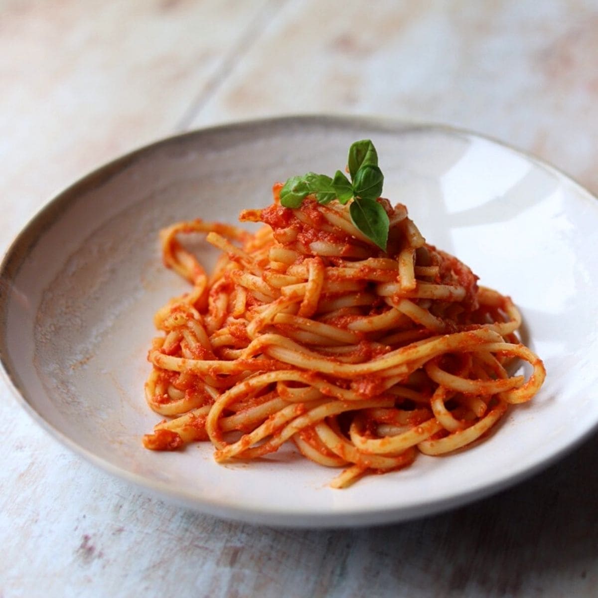 Linguine with tomato sauce and fresh basil in white bowl