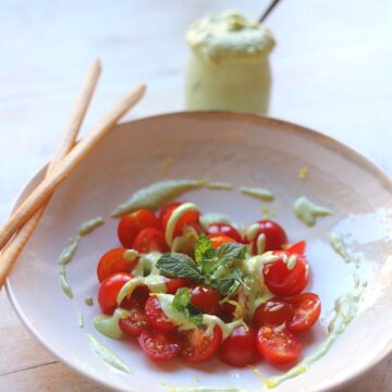 whipped feta dip over halved cherry tomatoes in a bowl