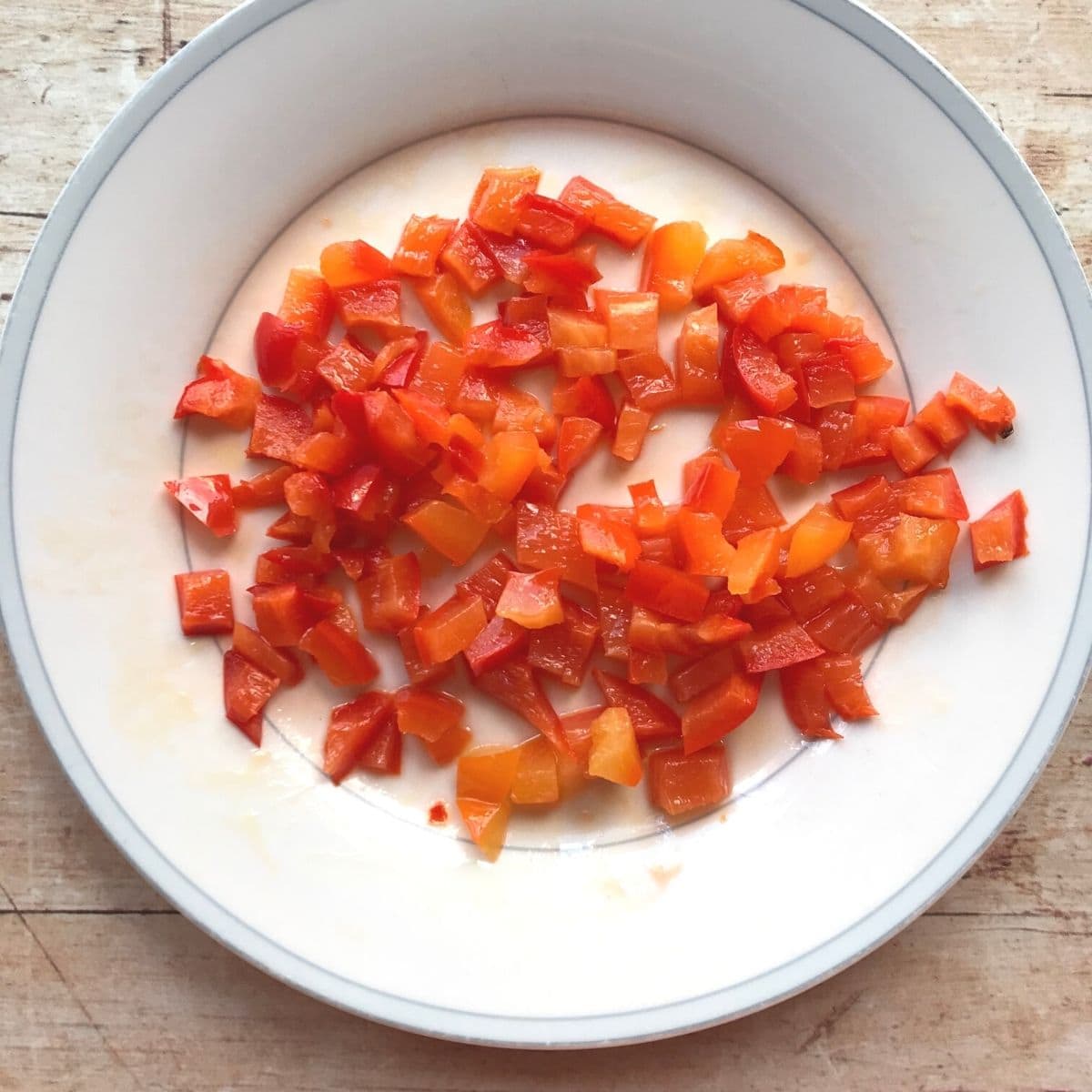 Chopped red bell pepper on a white plate.