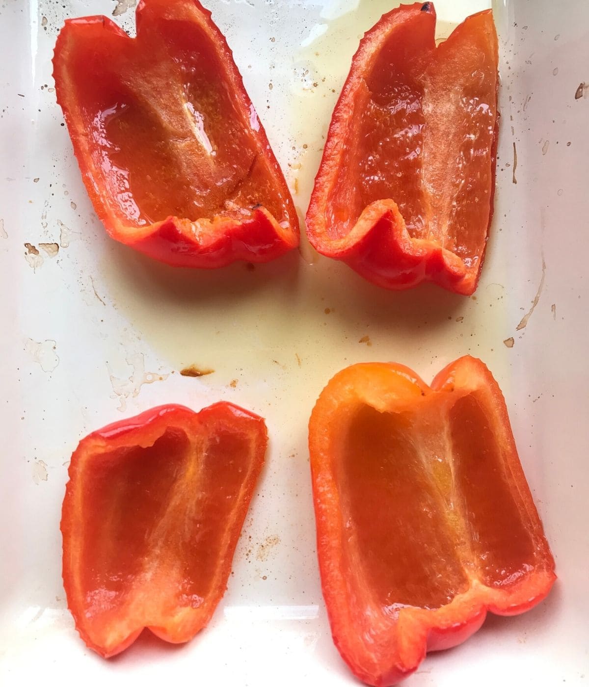 Grilled red bell peppers in pan with olive oil.