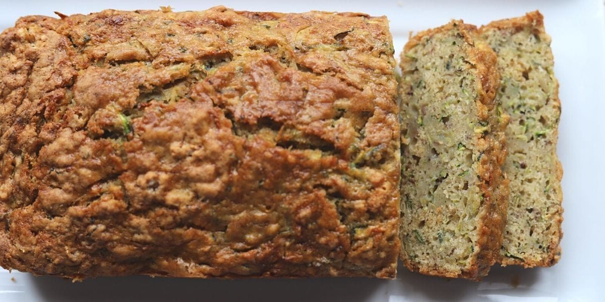 Whole loaf of zucchini banana bread partially sliced.