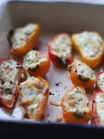 Close up of roasted stuffed peppers in a pan.