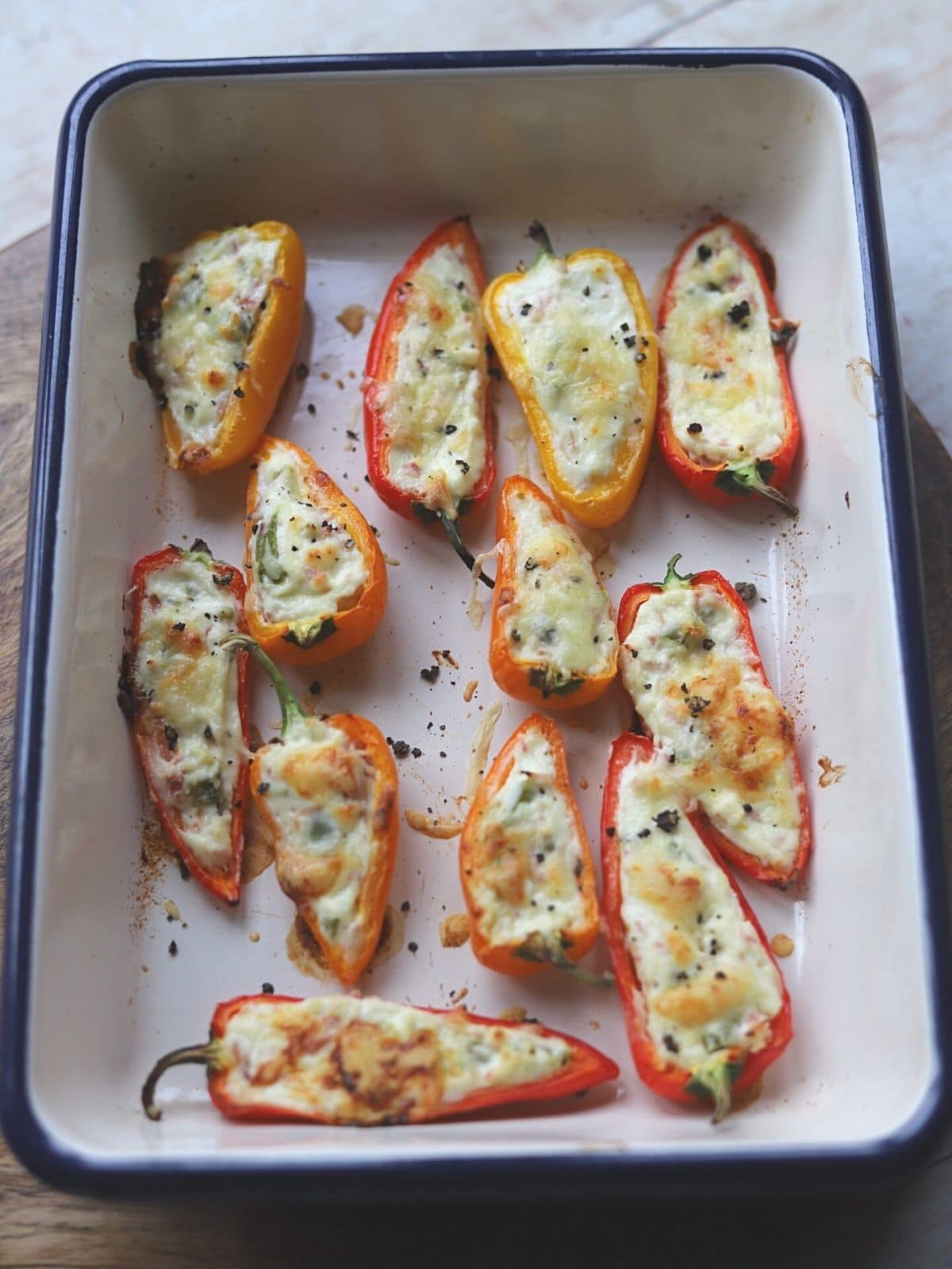 Roasted stuffed peppers in roasting dish.
