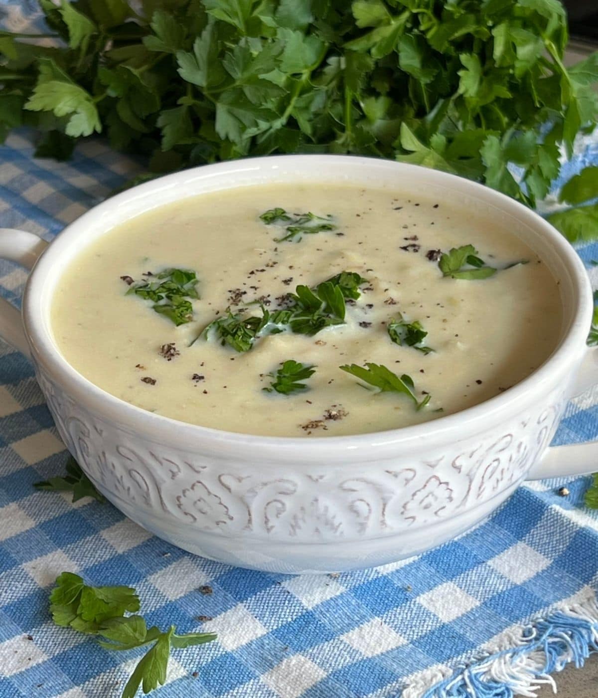 White bowl with Scottish smoked haddock soup garnished with parsley and parsley in the background.