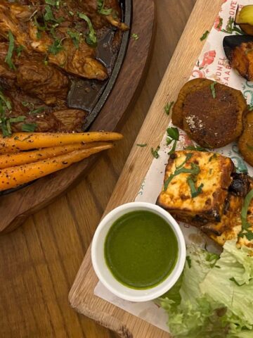 partial view of goat curry in dish and vegetarian platter.