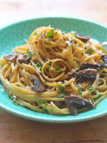Spaghetti with gorgonzola sauce and mushrooms in blue bowl.