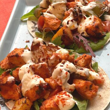 Two assembled spicy chicken wraps on a blue platter.