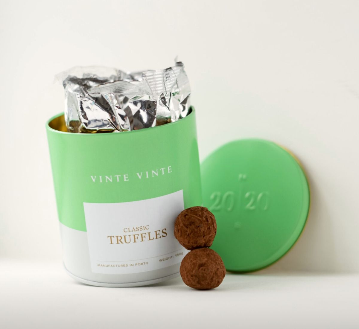 Green and white tin next to two chocolate truffles.
