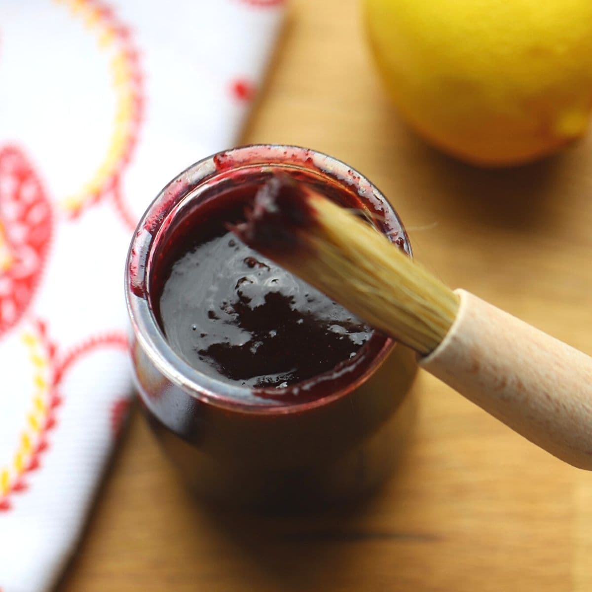 Cherry sauce in glass jar with pastry brush.