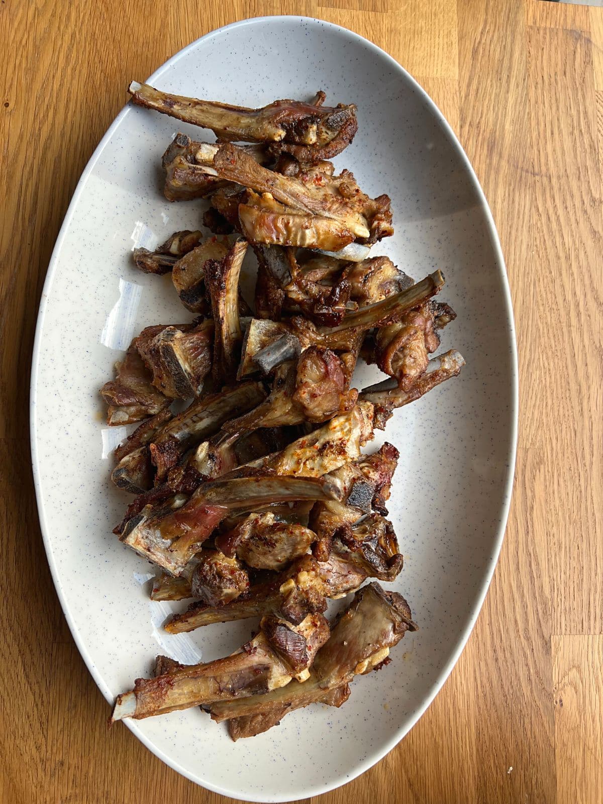 Overhead view of lamb ribs in white dish.