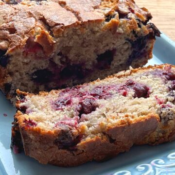 Slice of blueberry muffin loaf on a blue platter.