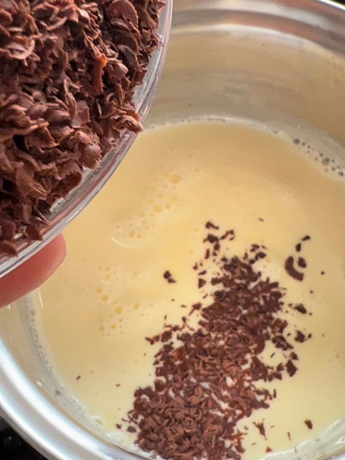 Pouring grated cocoa into the cream in pan.