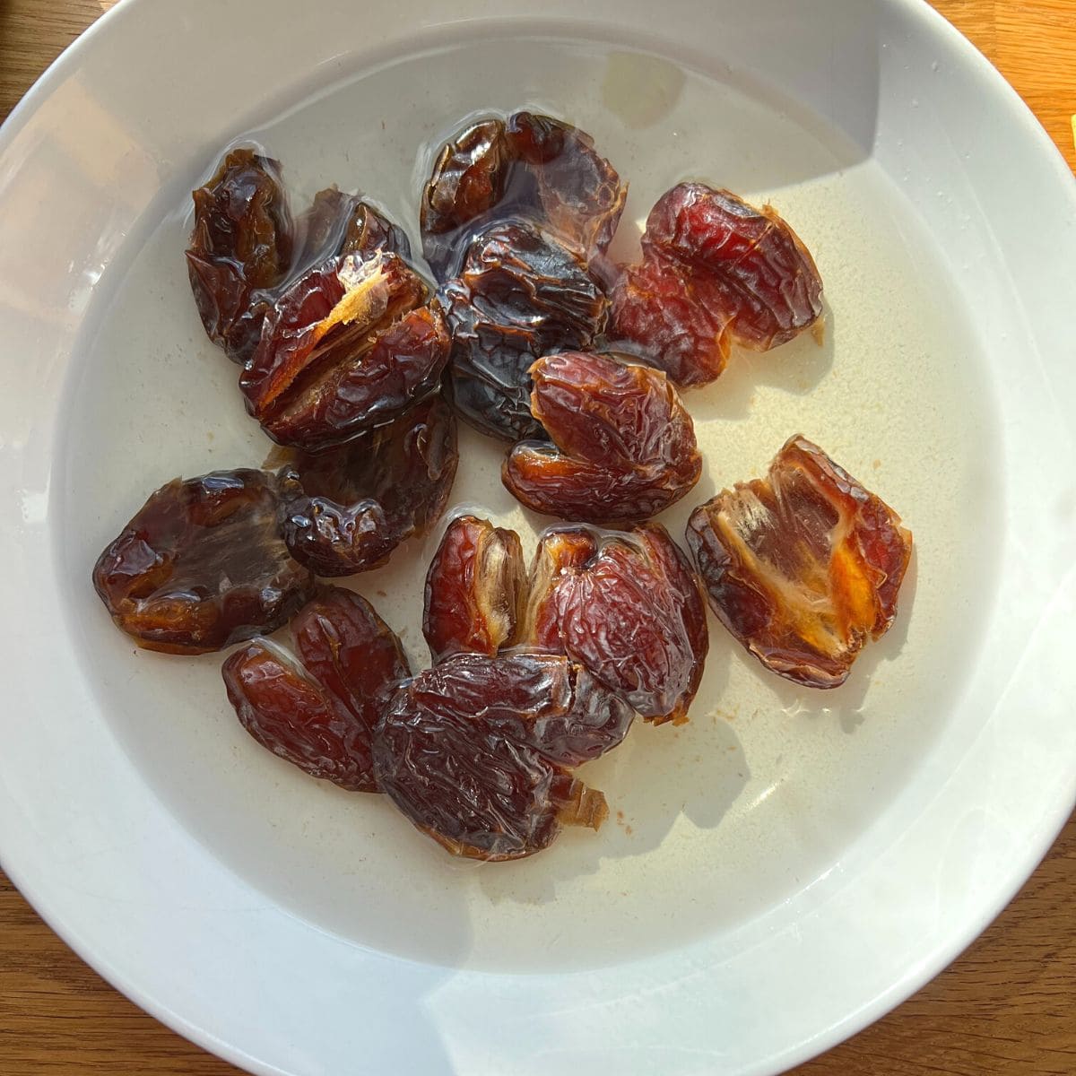 Dates soaking in water in a white bowl.