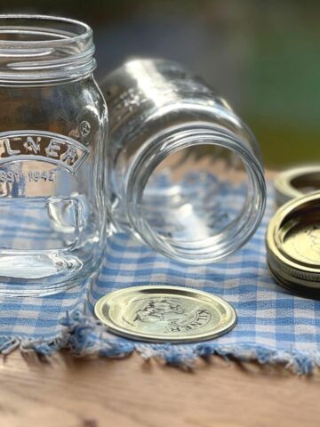 Empty Kilner glass jars next to their lids on a cloth.