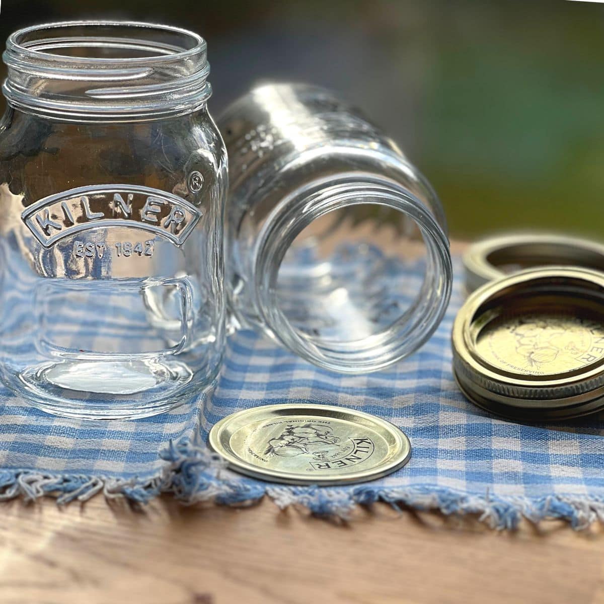 Empty Kilner glass jars next to their lids on a cloth.