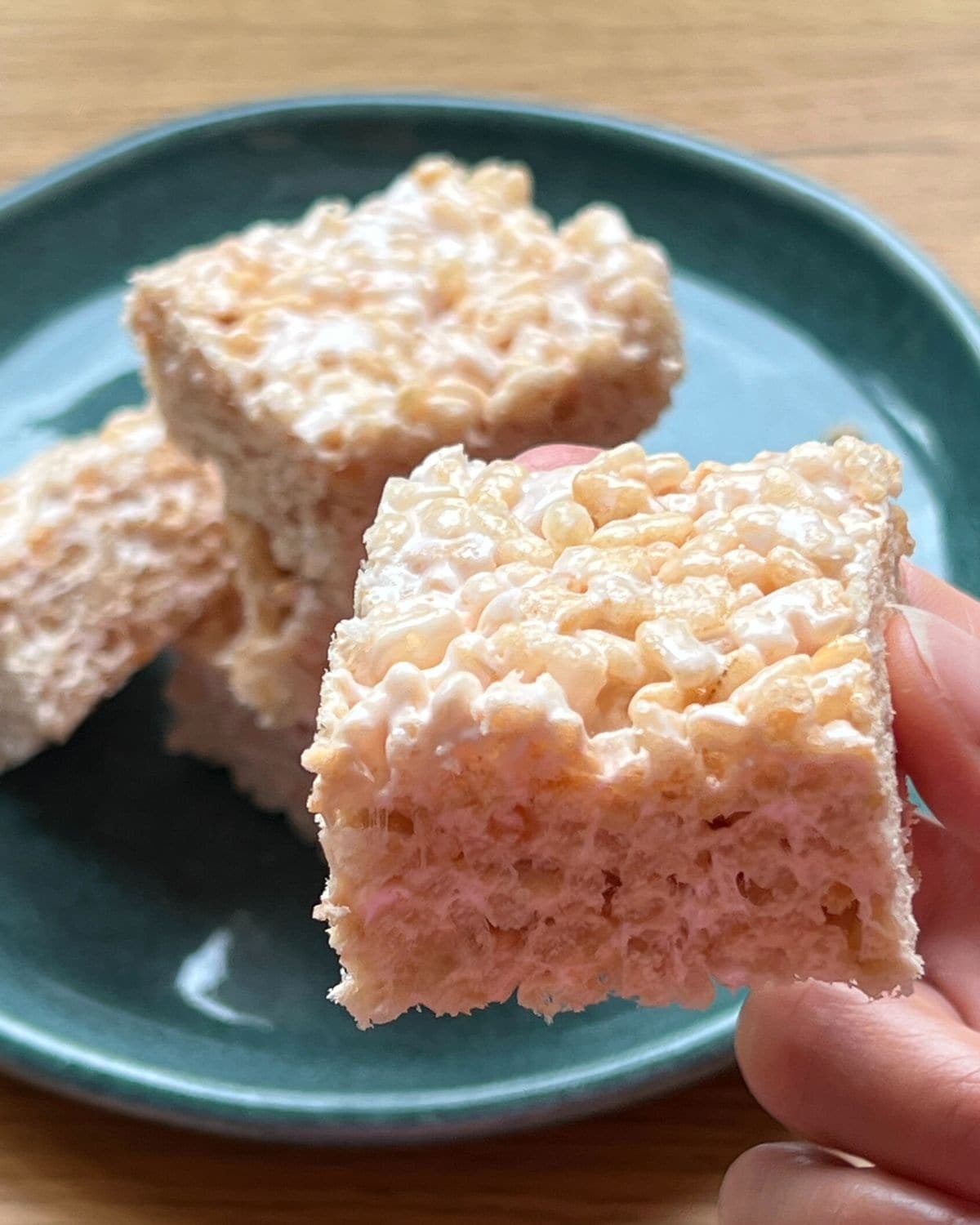 Close up of rice krispie square with plate of squares in background.